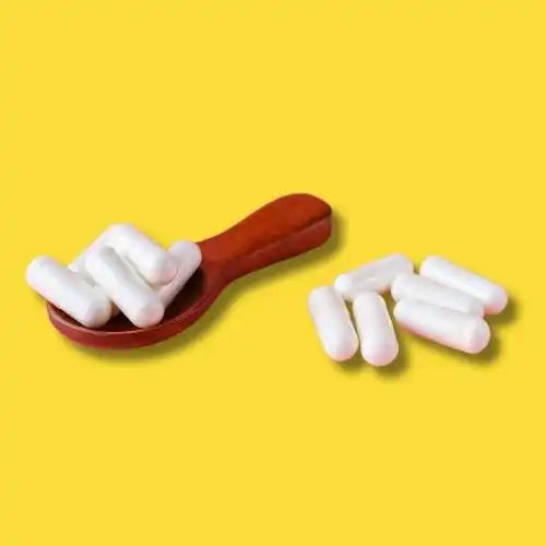 White capsule pills on and beside a wooden spoon.